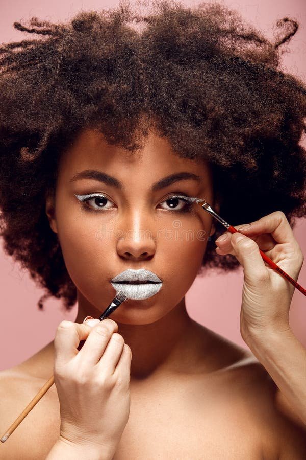 young african female isolated pink wall artists doing makeup coloring lips eyelids white model looking camera serious woman 109097339 1737794700